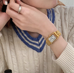 Reloj retro pequeño dorado con correa de acero de estilo antiguo.