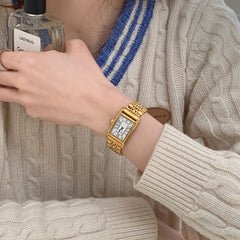 Reloj retro pequeño dorado con correa de acero de estilo antiguo.