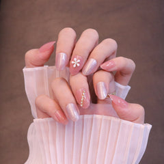 Uñas postizas redondeadas medianas en rosa claro con adornos de flores y cristales