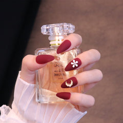 Uñas postizas en rojo mate almendra medio con adornos de flores y lunas