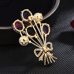 Broche de globos de cristal y perla con lazo