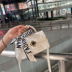 Kleine gesteppte Umhängetasche mit Blumenverschluss und geflochtenem Griff