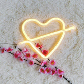 Letrero luminoso de neón con forma de corazón y flecha