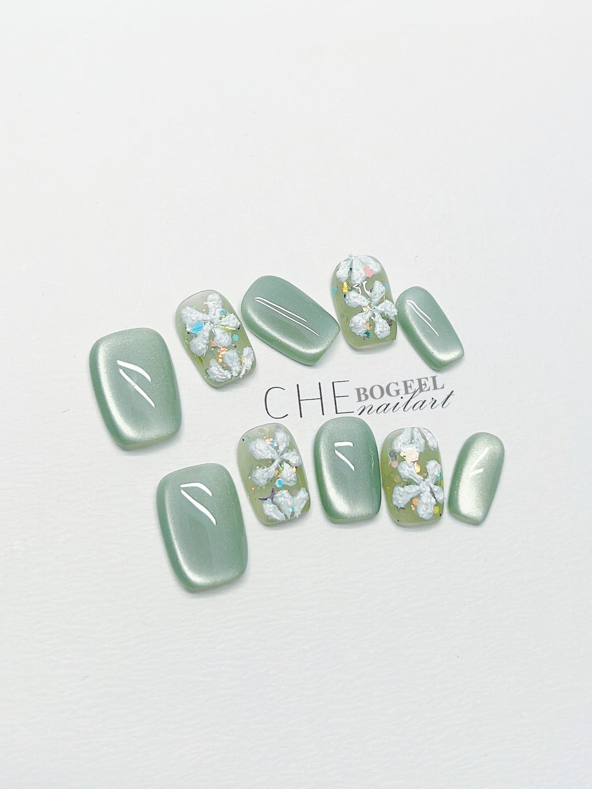 Handgetragener Nagel Grünes Katzenauge Dreidimensionale geprägte Blumen