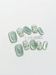 Handgetragener Nagel Grünes Katzenauge Dreidimensionale geprägte Blumen