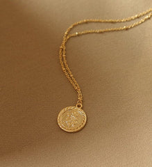 Collar con dije de moneda en relieve dorado