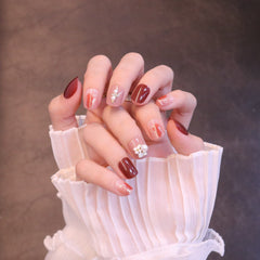 Uñas postizas cortas, cuadradas y ovaladas en rojo con adornos de flores y perlas