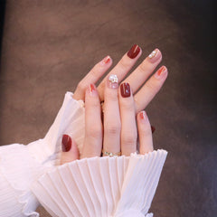 Uñas postizas cortas, cuadradas y ovaladas en rojo con adornos de flores y perlas