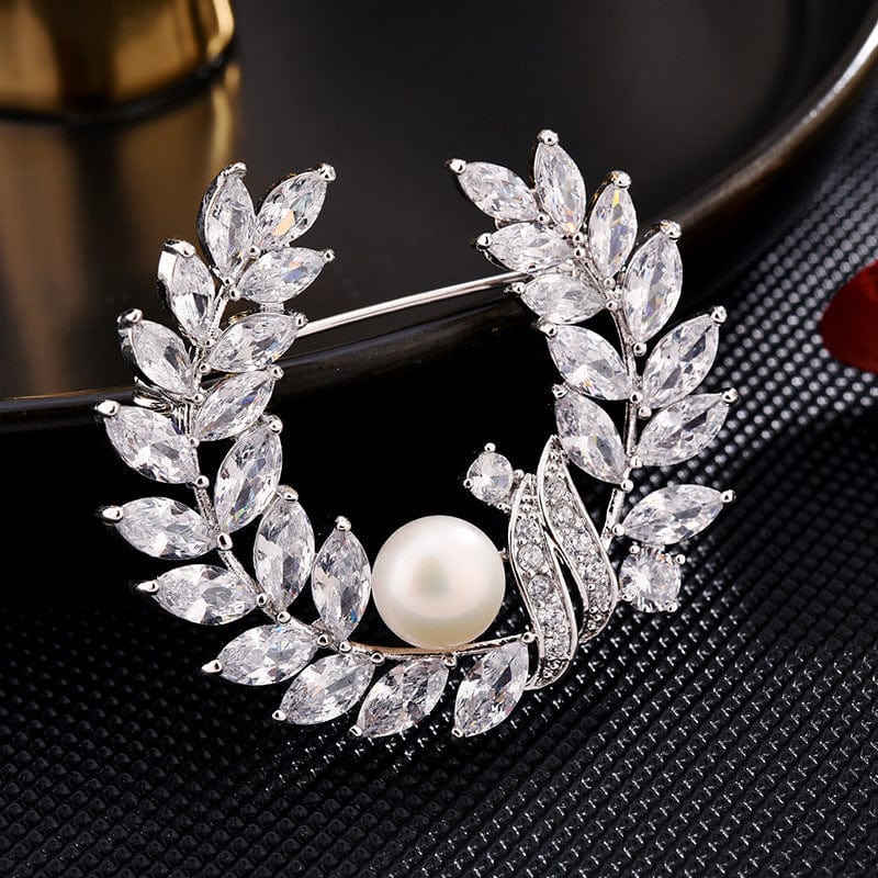 Broche de cristal transparente con corona floral y perla