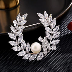 Broche de cristal transparente con corona floral y perla