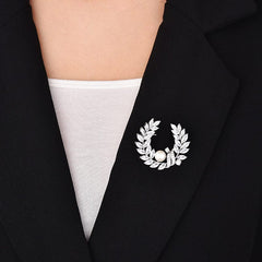 Broche de cristal transparente con corona floral y perla