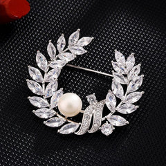 Broche de cristal transparente con corona floral y perla